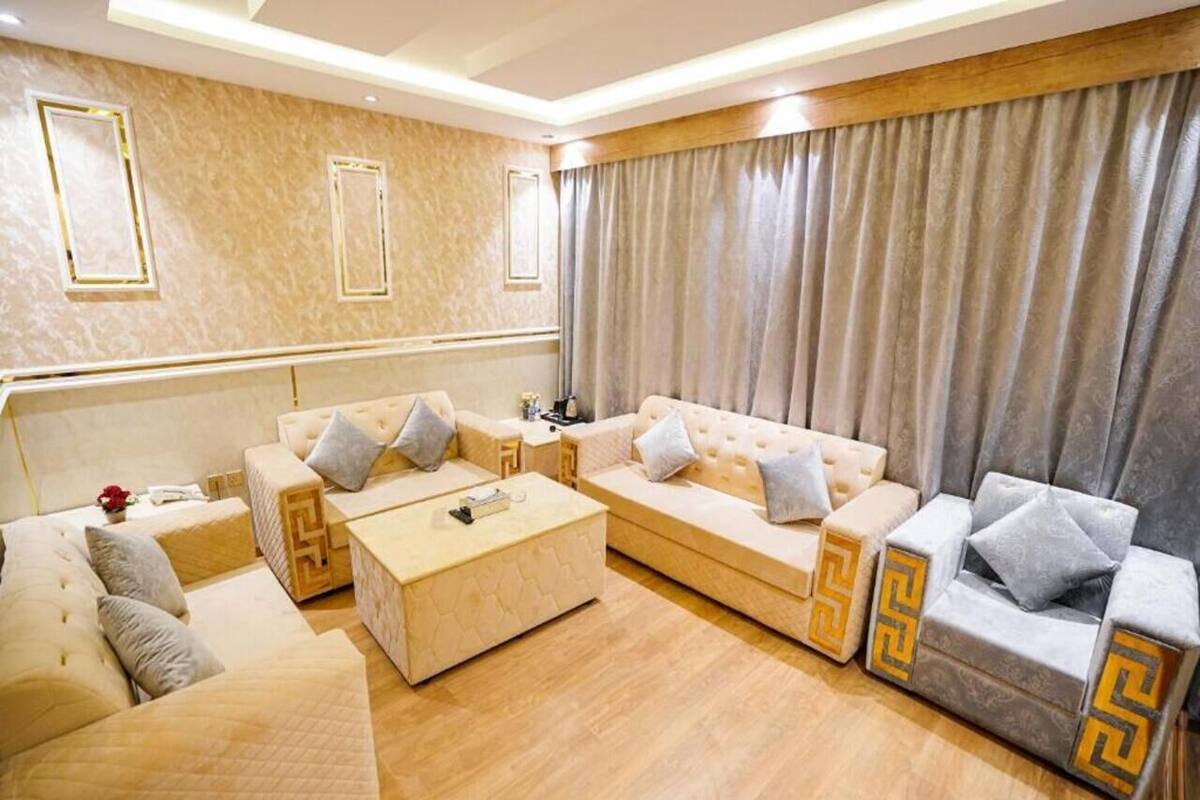 A modern living room with a beige sofa set, a coffee table, and a patterned rug.