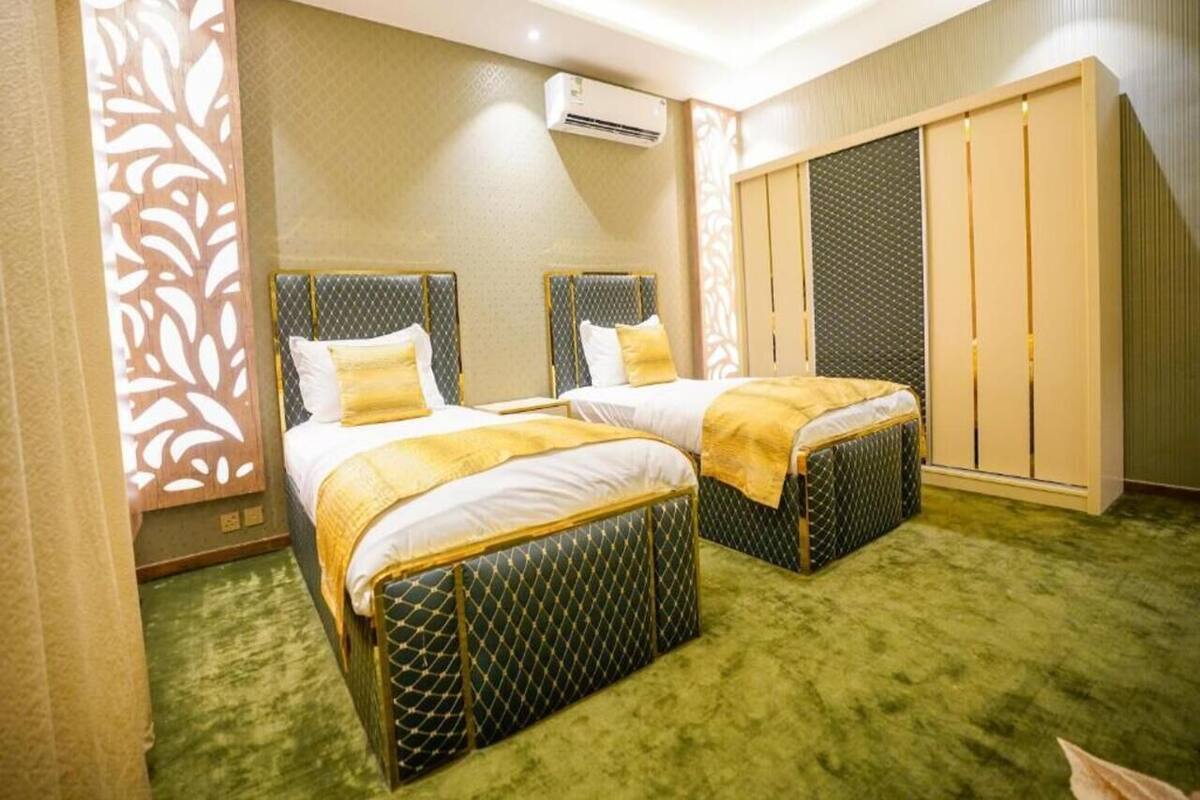 A hotel room with two beds, a wardrobe, and an air conditioning unit.