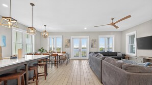 A spacious living area with a large sofa, dining table, and chairs. There are ceiling fans and pendant lights. - Huge Waterfront Home - Sleeps 20, private pool (gulf shores)