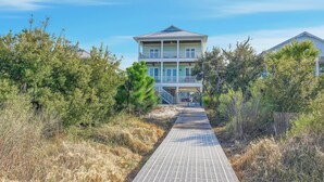 A two-story house with a covered porch and a pathway leading to the entrance. - Huge Waterfront Home - Sleeps 20, private pool (gulf shores)