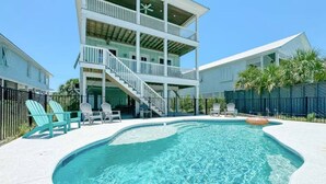 A two-story building with a swimming pool, outdoor chairs, and a staircase leading to the upper level. - Huge Waterfront Home - Sleeps 20, private pool (gulf shores)