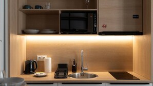 Un angolo cottura compatto dotato di forno a microonde, lavello e macchina del caffè.