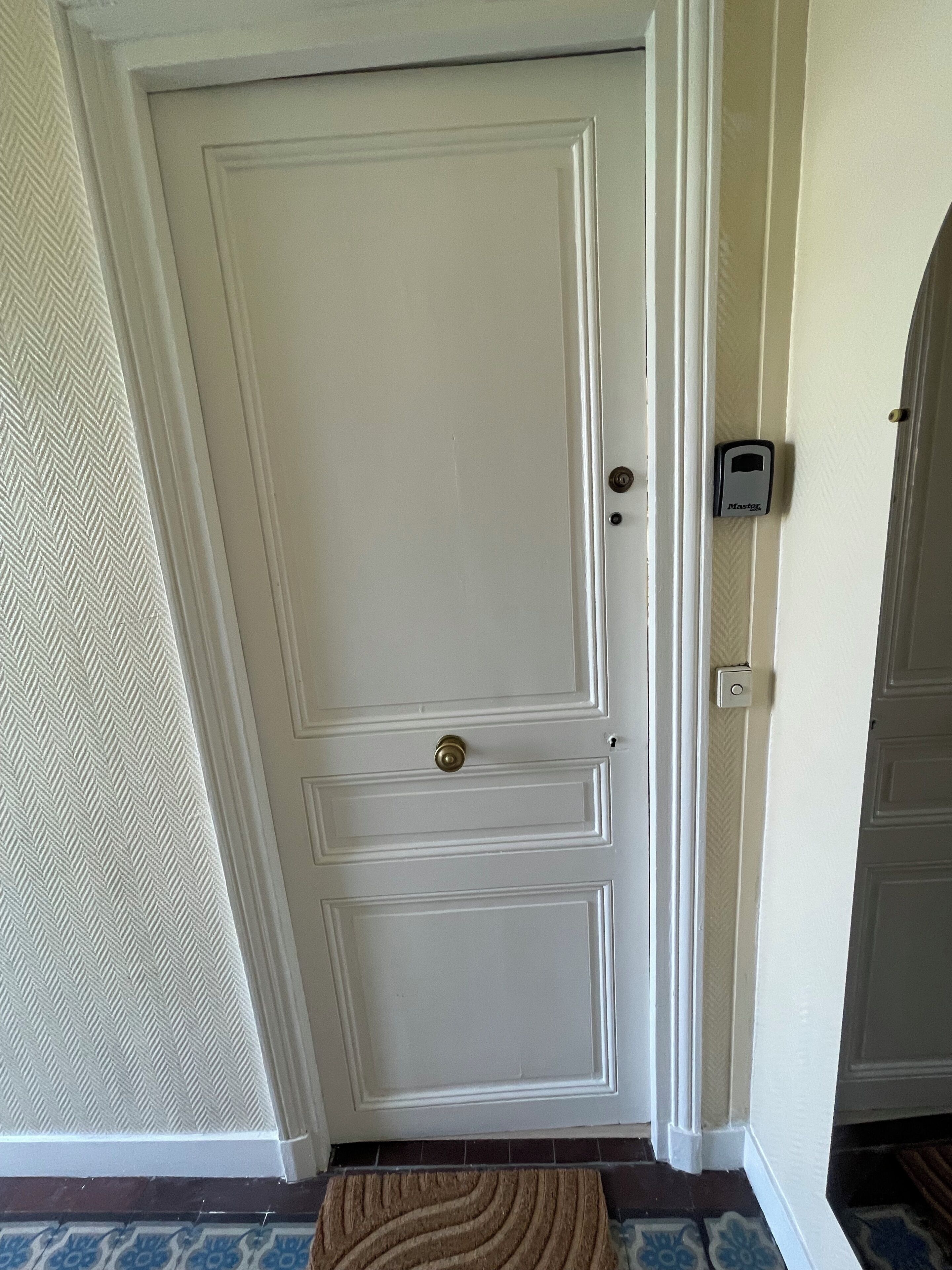Una porta blanca amb un pom de bronze i un tancament de codi.