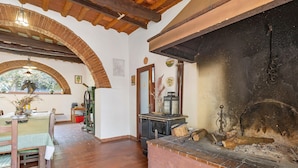 A rustic interior with a fireplace, wooden furniture, and a tiled floor.