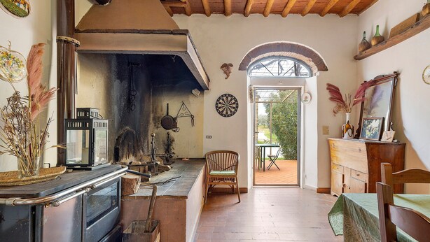 A rustic kitchen with a stove, wooden cabinets, and a dining area with a table and chairs.