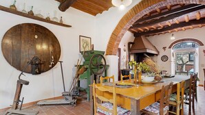 A rustic dining area with a wooden table, chairs, and a large wooden wheel.