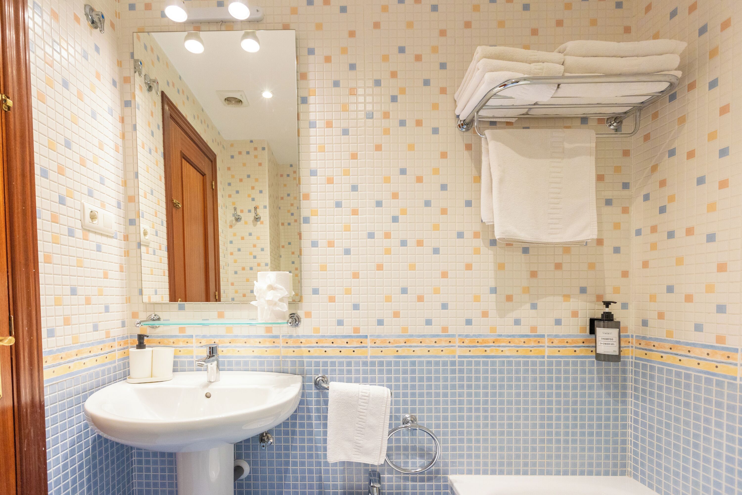 A bathroom with a sink, mirror, and towel rack.