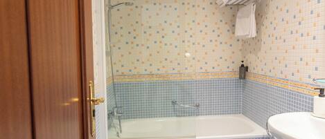 A bathroom with a bathtub, two toilets, a sink, and a shower.