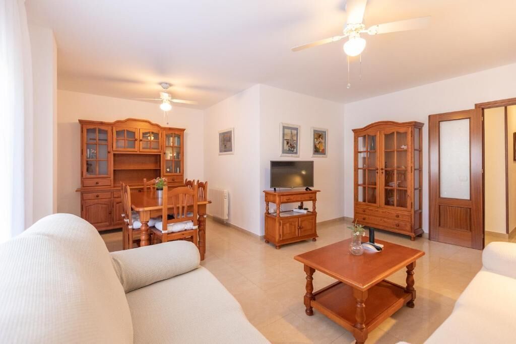 A living room with a sofa, wooden cabinets, a television, and a ceiling fan.