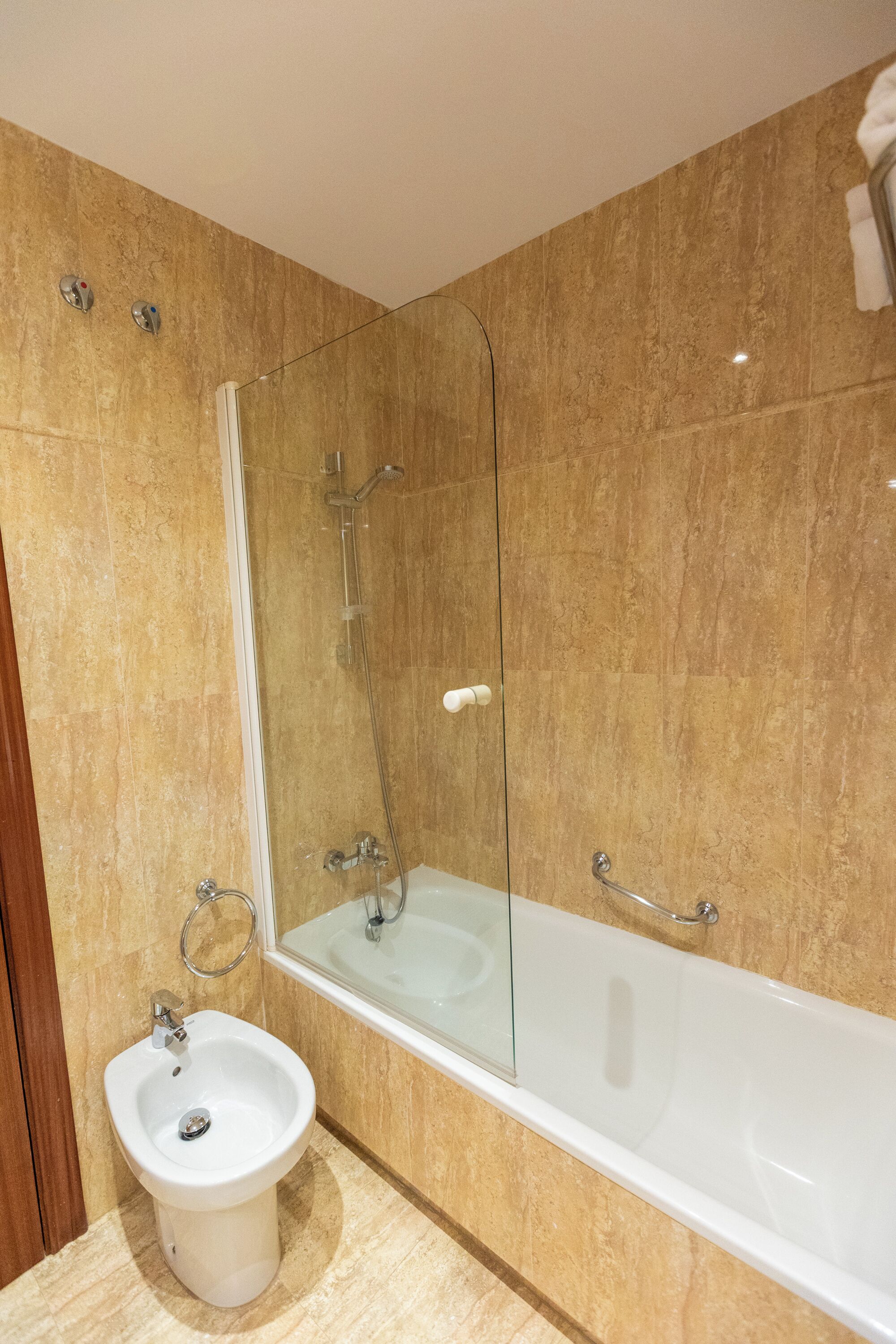 A bathroom with a bidet, a glass-enclosed shower, and a bathtub.