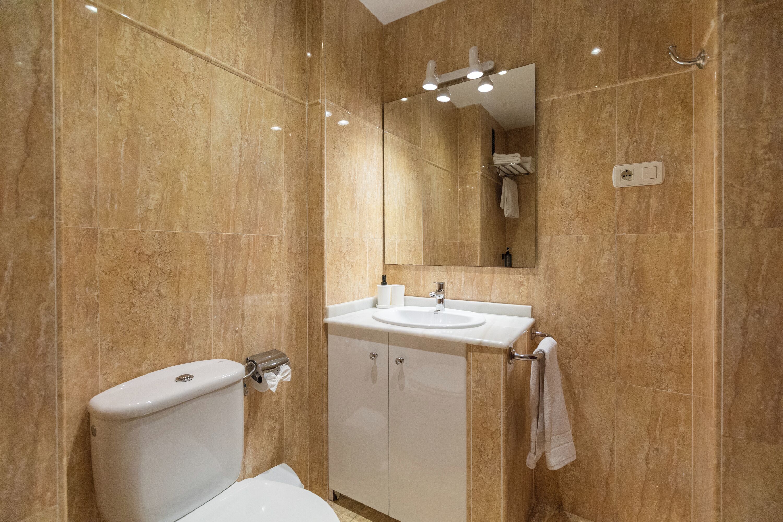 A bathroom with a toilet, sink, mirror, and towel rack.