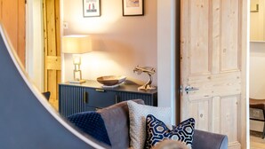 Ein modernes Wohnzimmer mit blauem Sofa, Holztür und gerahmten Kunstwerken an der Wand.