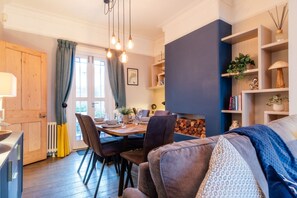 Un salon chaleureux comprenant un coin repas, une cheminée et une bibliothèque.