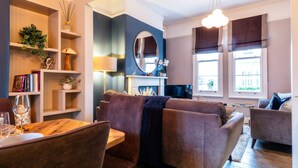 Ein modernes Wohnzimmer mit einer Couch, Sesseln, einem Esstisch und einem Kamin.