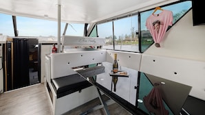 A boat interior with a table, a bottle of champagne, and a t-shirt hanging on the window.