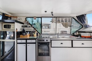 Cocina compacta para autocaravana con microondas, estufa, horno y lavamanos.