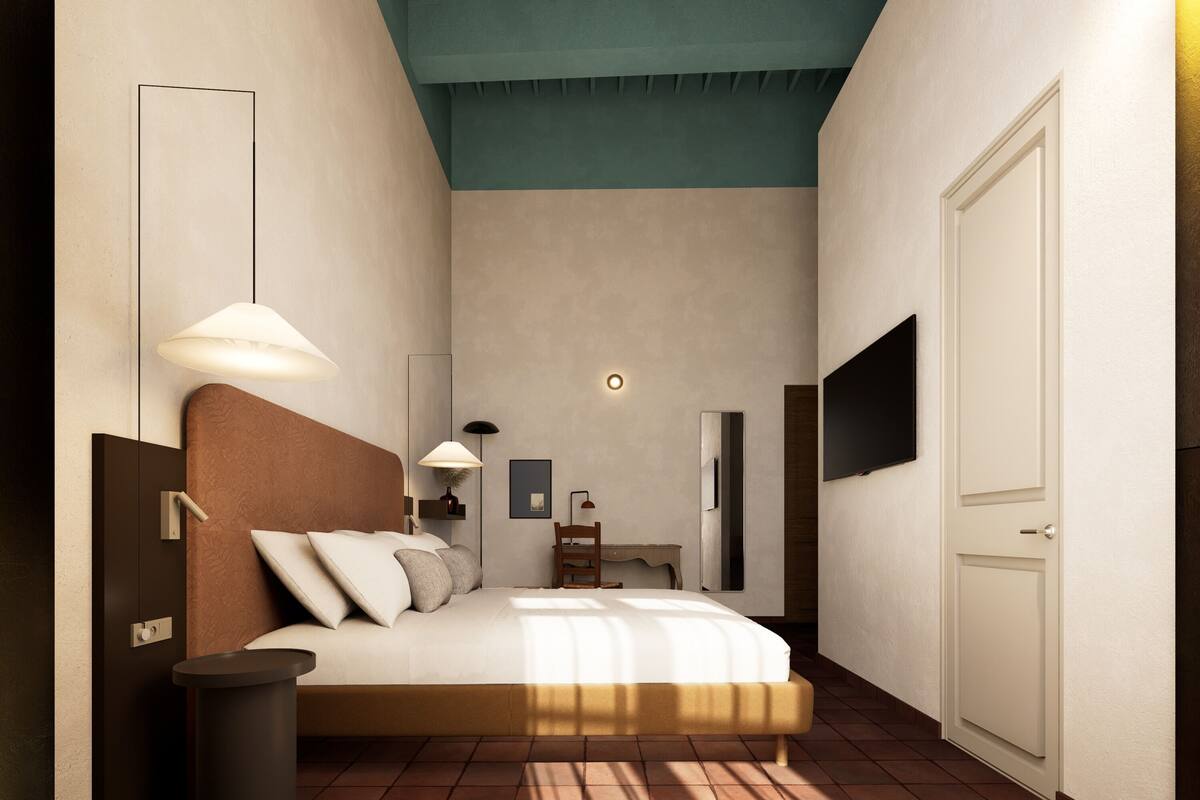 A bedroom with a bed, bedside lamps, a desk, a chair, a TV, and a door.