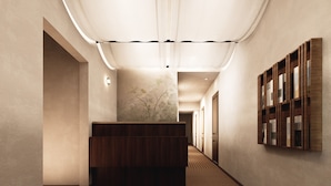 A hallway with a wooden reception desk, a wall-mounted bookshelf, and a patterned carpet. - BYPILLOW Del Presto (Florence)