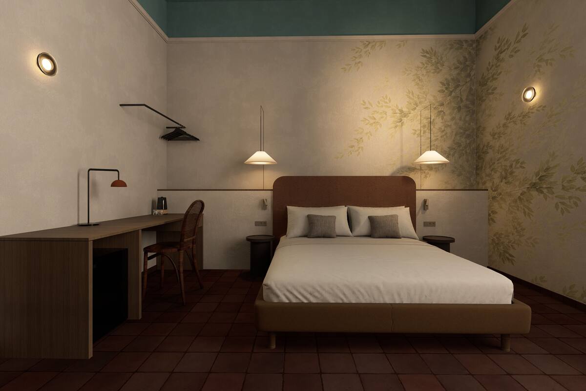 A bedroom with a bed, bedside tables, a desk, and a chair.