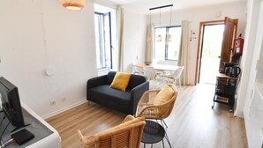 Una sala de estar moderna con un sofá, sillas, una mesa de comedor y una zona de cocina con una cafetera.