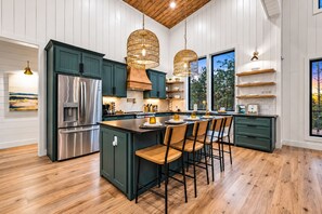 A modern kitchen with a central island, stainless steel appliances, and pendant lighting. - Luxe & Kid Approved! Playset, EV, Meta VR Game (Broken Bow)