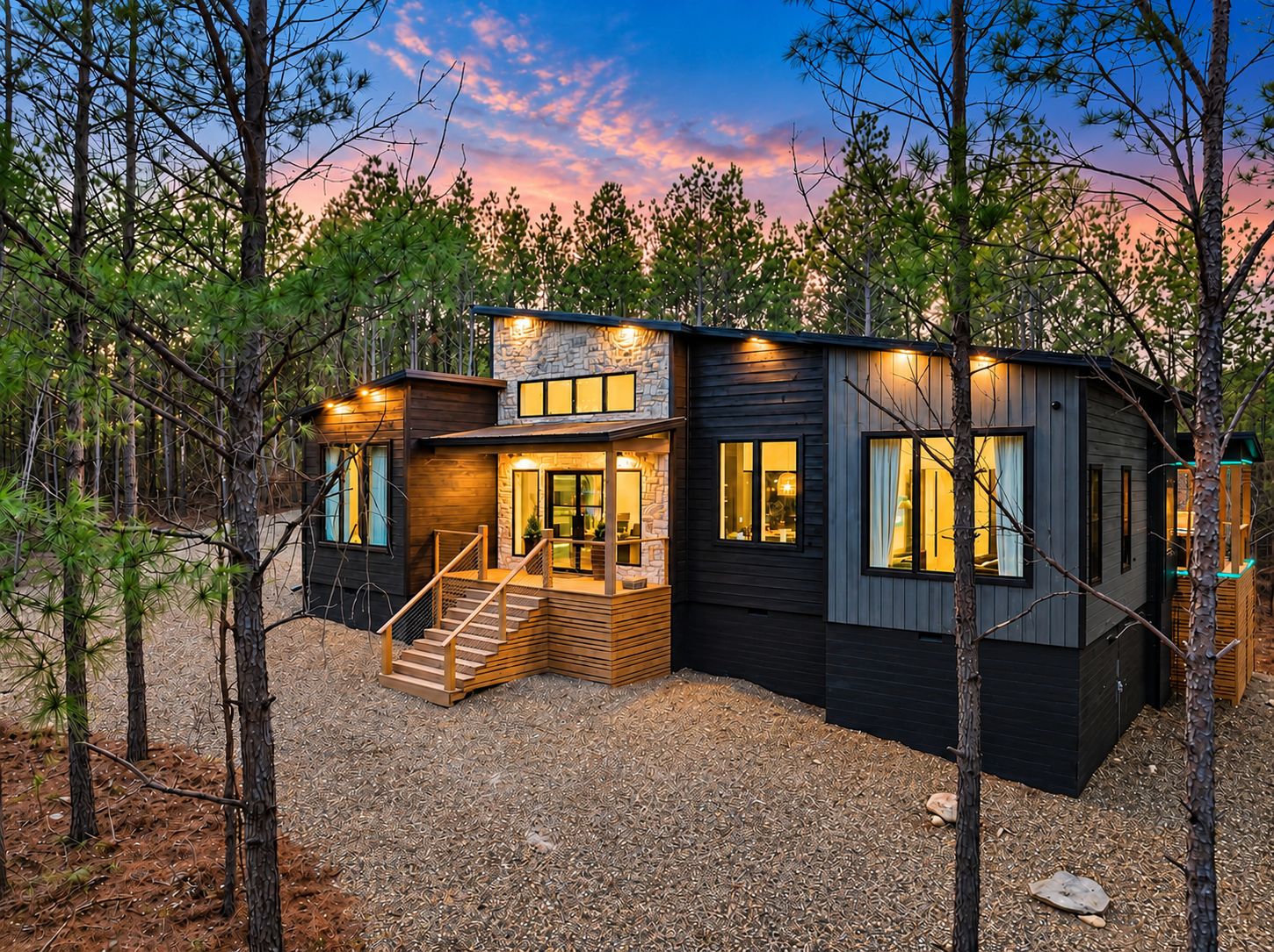 Una cabaña moderna con fachada de piedra, ventanas amplias y una terraza de madera.