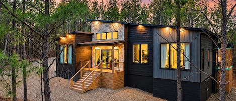 Una cabaña moderna con fachada de piedra, ventanas amplias y una terraza de madera.