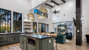 A modern kitchen with a central island, large windows, and a ceiling fan. - Fall Promo! Luxe & Kid Approved! Playset, EV (Broken Bow)