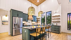A modern kitchen with a central island, stainless steel appliances, and pendant lighting. - Fall Promo! Luxe & Kid Approved! Playset, EV (Broken Bow)