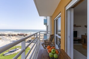 A balcony with a view of the beach, a table with fruit, and a TV in the living area. - #370 1BR Riamar | Sea View & Central (Armação de Pêra)