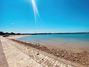 A paved walkway along a calm body of water with a clear sky above. - Bright studio in the heart of the Old Market (La Rochelle)