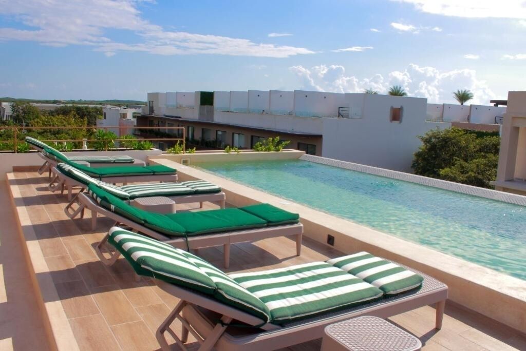A rooftop pool area with lounge chairs and a clear view of the surrounding buildings.