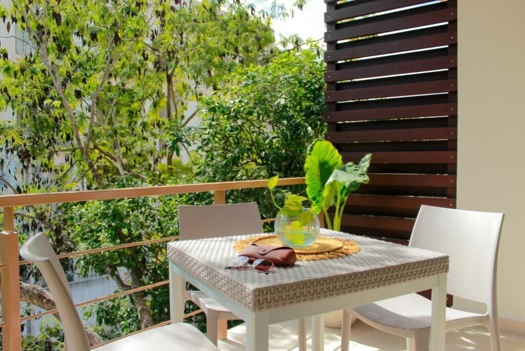 A balcony with a table set for two, surrounded by greenery.