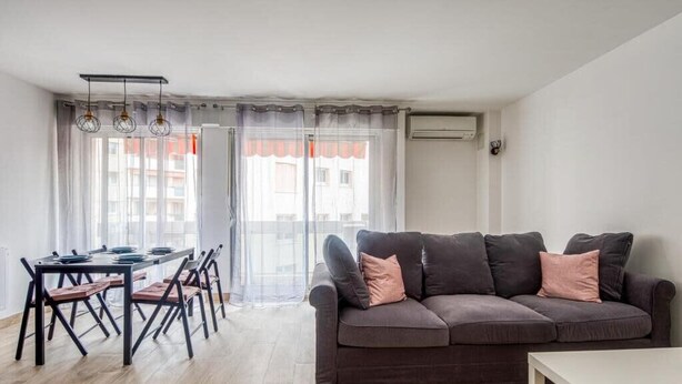 A modern living room with a sofa, dining table, chairs, and a view through a large window. - Bright apartment with a view in Antibes (Antibes)