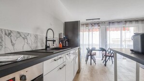 A modern kitchen with a built-in oven, a sink, and a dining area with a table and chairs. - Bright apartment with a view in Antibes (Antibes)