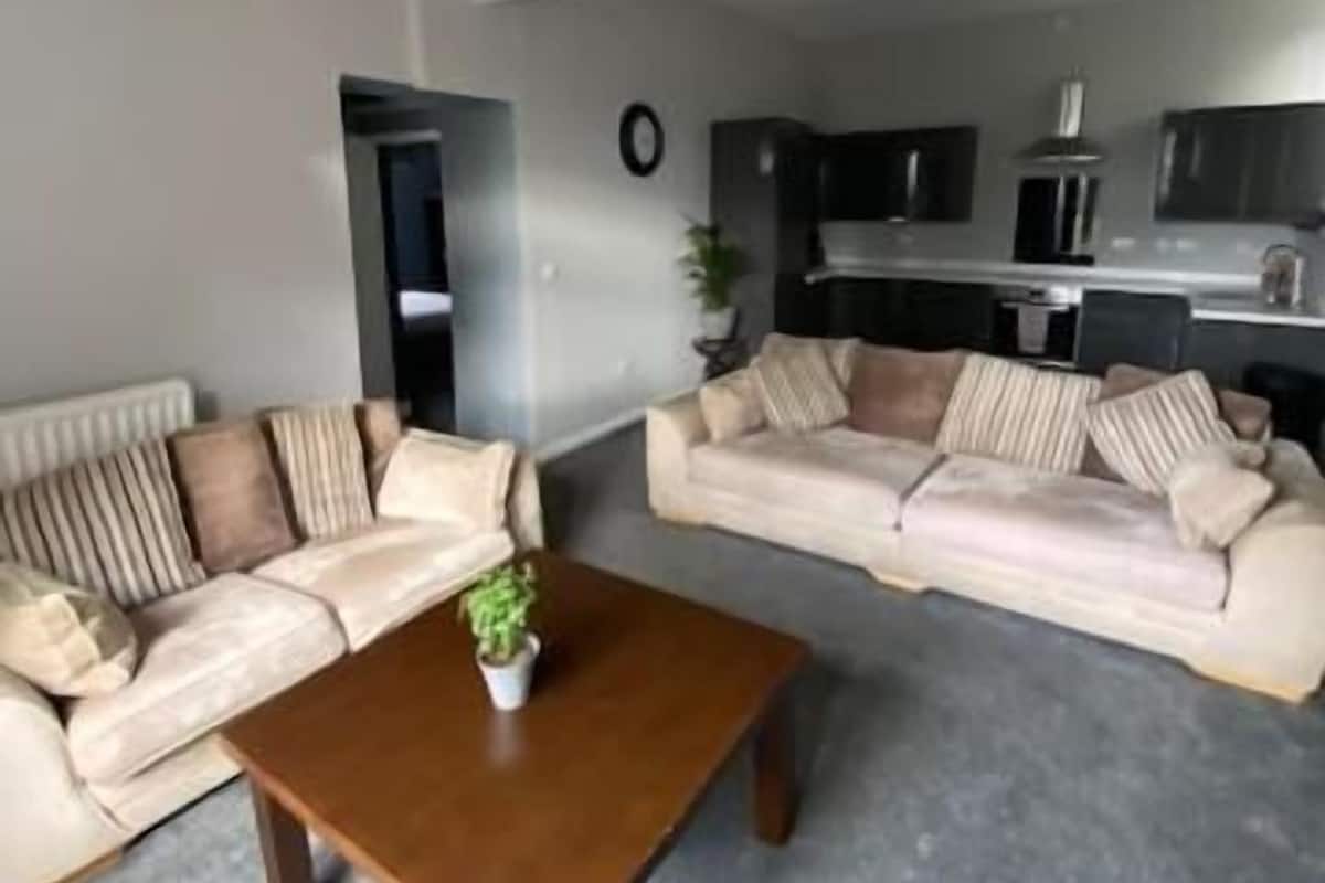 Ein modernes Wohnzimmer mit zwei Sofas, einem Couchtisch und einer Küche im Hintergrund.