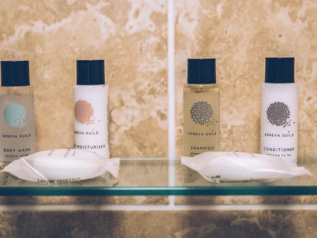 Quatre bouteilles de produits de la marque Geneva Guild, alignées sur une étagère.