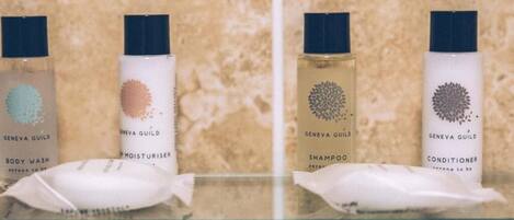Quatre bouteilles de produits de la marque Geneva Guild, alignées sur une étagère.