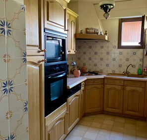 Eine Küche mit Holzausstattung, einem schwarzen Backofen und einem Fenster über der Spüle.