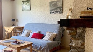 Een gezellige woonkamer met een bank, een bijzettafeltje en een open haard.
