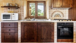 A kitchen with a microwave, stove, oven, and wooden cabinets. - Holiday Home 'Colline' with Balcony and Wi-Fi (Radicofani)