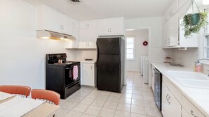 A kitchen with white cabinets, a black refrigerator, a stove, and a sink. - Peaceful 3-bedroom house in quiet neighborhood with mature trees. (Wichita)