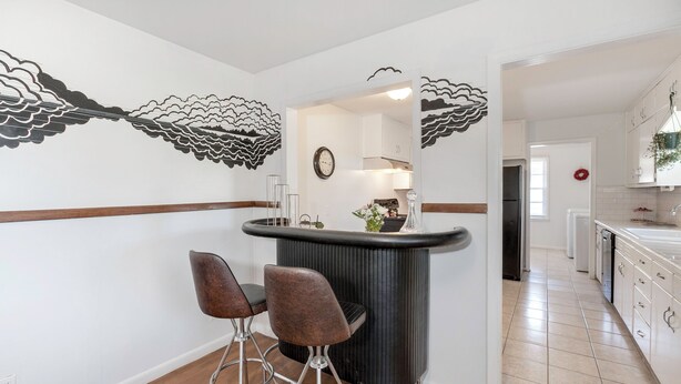 A modern kitchen with a central island, bar stools, and a decorative wall mural. - Peaceful 3-bedroom house in quiet neighborhood with mature trees. (Wichita)