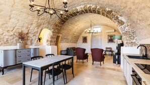 A spacious kitchen with a stone archway, modern furniture, and a chandelier. - Casa Labisi - One Bedroom Apartment, Sleeps 4 (Noto)