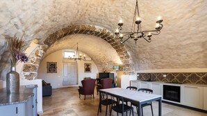 An arched stone ceiling, a dining area with a table and chairs, and a kitchen with white cabinets. - Casa Labisi - One Bedroom Apartment, Sleeps 4 (Noto)