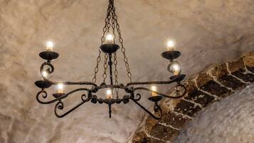 Um candelabro com várias luzes, suspenso por uma corrente em frente a uma parede texturizada.