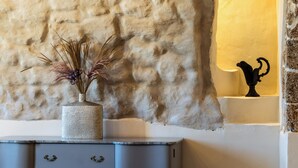 A textured wall, a vase with dried plants, a cabinet with drawers, and a wall-mounted light fixture. - Casa Labisi - One Bedroom Apartment, Sleeps 4 (Noto)