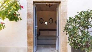 An open doorway leading to a room with a bed, a chandelier, and wall-mounted mirrors. - Casa Labisi - One Bedroom Apartment, Sleeps 4 (Noto)