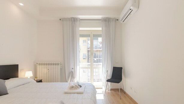 A hotel room with a bed, a chair, a radiator, and a window with curtains. - Moderno e comodo Metro Lucio Sestio (Rome)