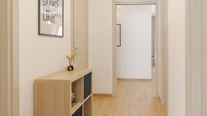 A hallway with a wooden console table, a framed quote on the wall, and a door at the end. - Moderno e comodo Metro Lucio Sestio (Rome)
